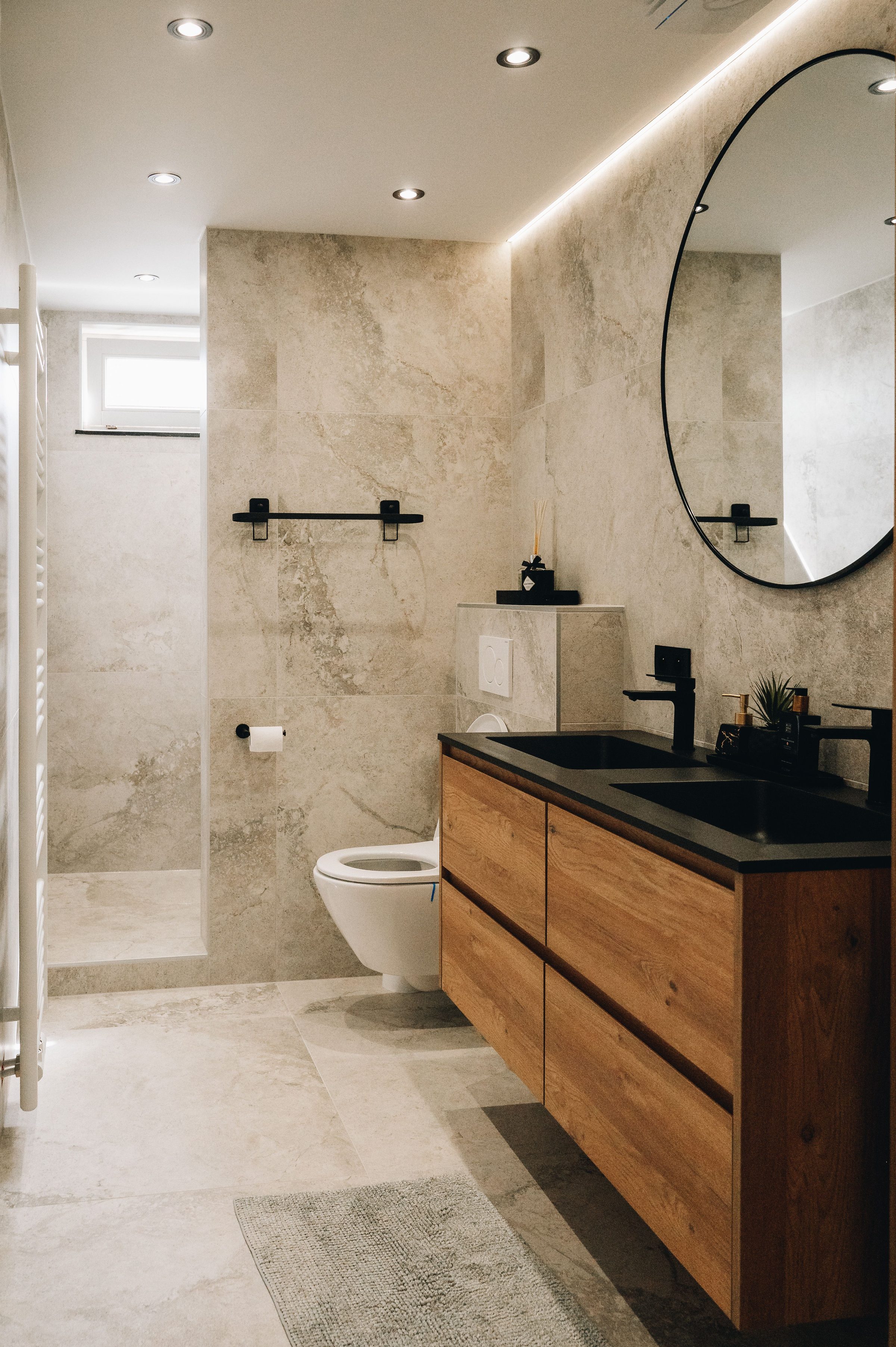 Walk-in shower remodel with full-slab marble walls, sliding glass enclosure, and a quartz-counter vanity with backlit mirror.